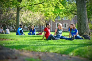 Students outdoors sitting in grassy area