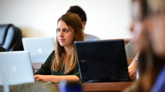 Female student sitting in a classroom with an open laptop